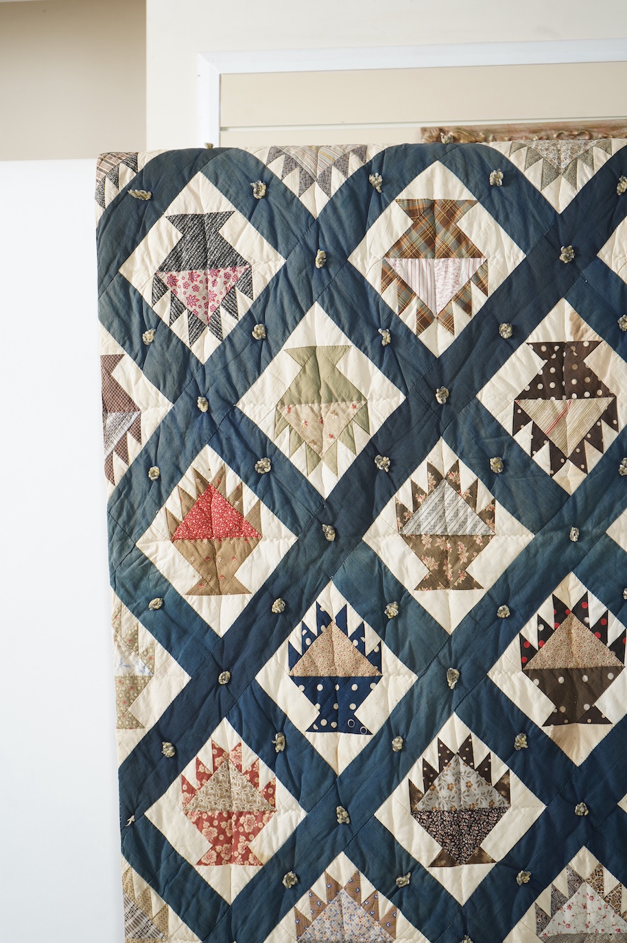 A bold handsome, American, Vermont 1865 (Civil War) ‘basket’ and lattice, hand quilted and piece tied bedcover, with an ornate floral backing. Worked with a plain navy cotton lattice border around central stylised printe